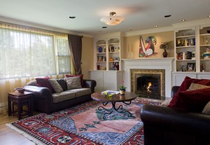 LIVING ROOM WITH NEW FIREPLACE TREATMENT, CABINETS. ANTIQUE CARPET SETS OFF FATHER’S CONTEMPORARY PAINTINGS.