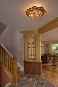 RECLAIMED, RESTORED ANTIQUE STAINED GLASS PANEL DEFINES FOYER, NEW RAILING OPENS SPACE TO VIEW.